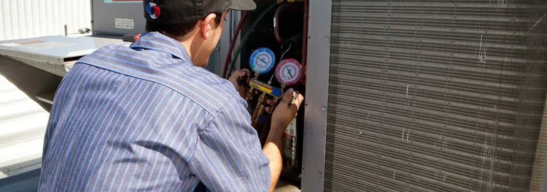HVAC technician servicing a condenser unit in Grayson