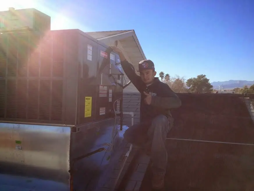 HVAC technician performing Heat Pump Repair on a rooftop unit in Grayson